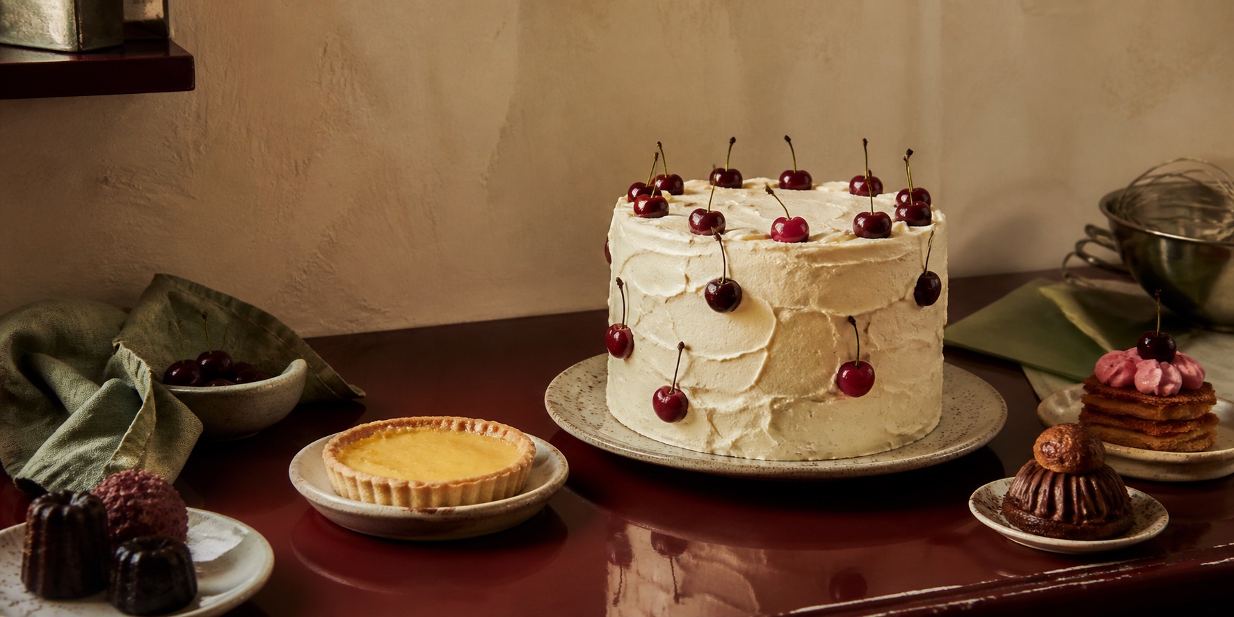Tarta artesanal de crema y cerezas junto a pequeños dulces